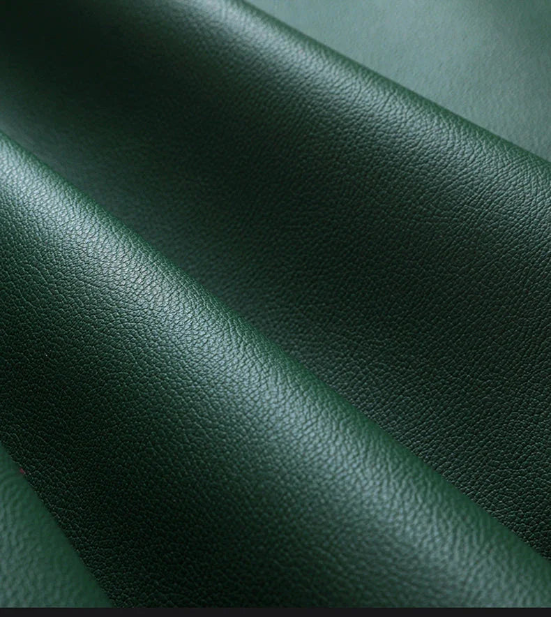 Close-up of dark green textured leather material with soft folds and natural grain detail