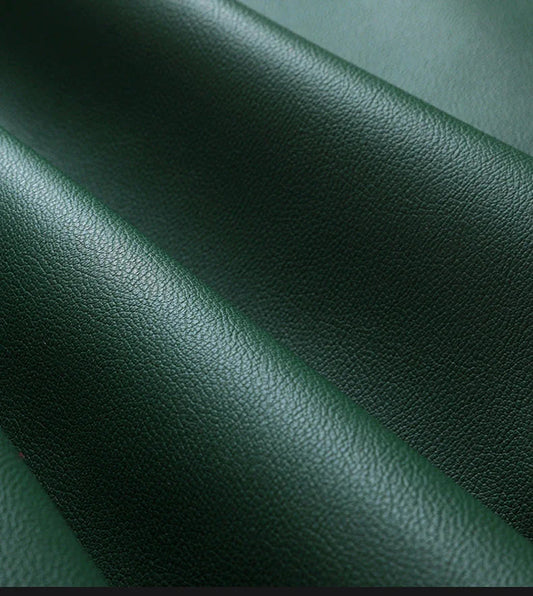 Close-up of dark green textured leather material with soft folds and natural grain detail
