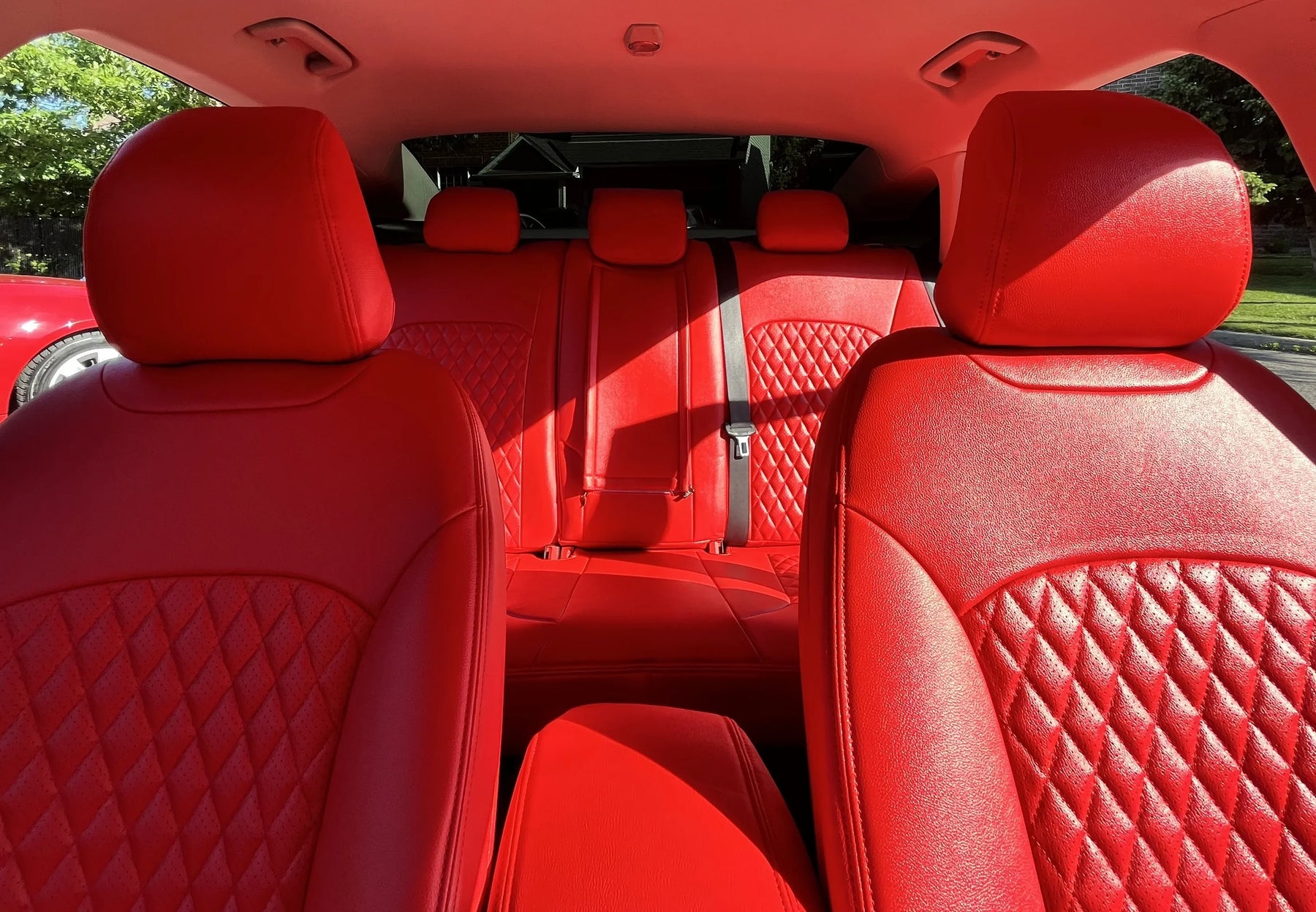Luxury custom red diamond-stitched car seat covers on front and back seats, bright sunlight
