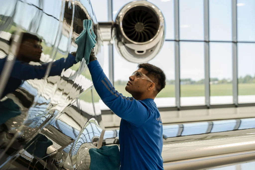 Technician performing aircraft exterior detailing inside hangar in Orleans