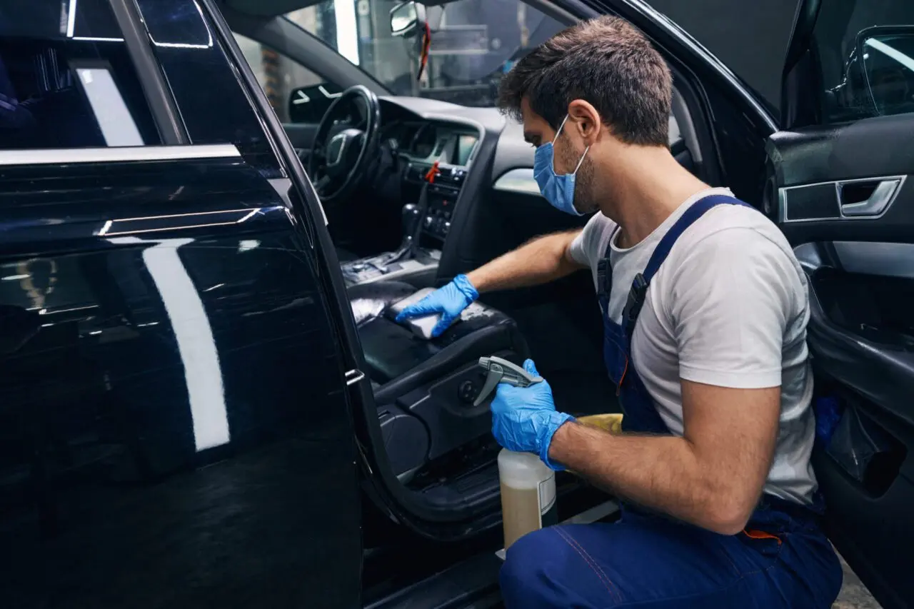 male-wiping-seat-clean-in-black-car-during-detailing